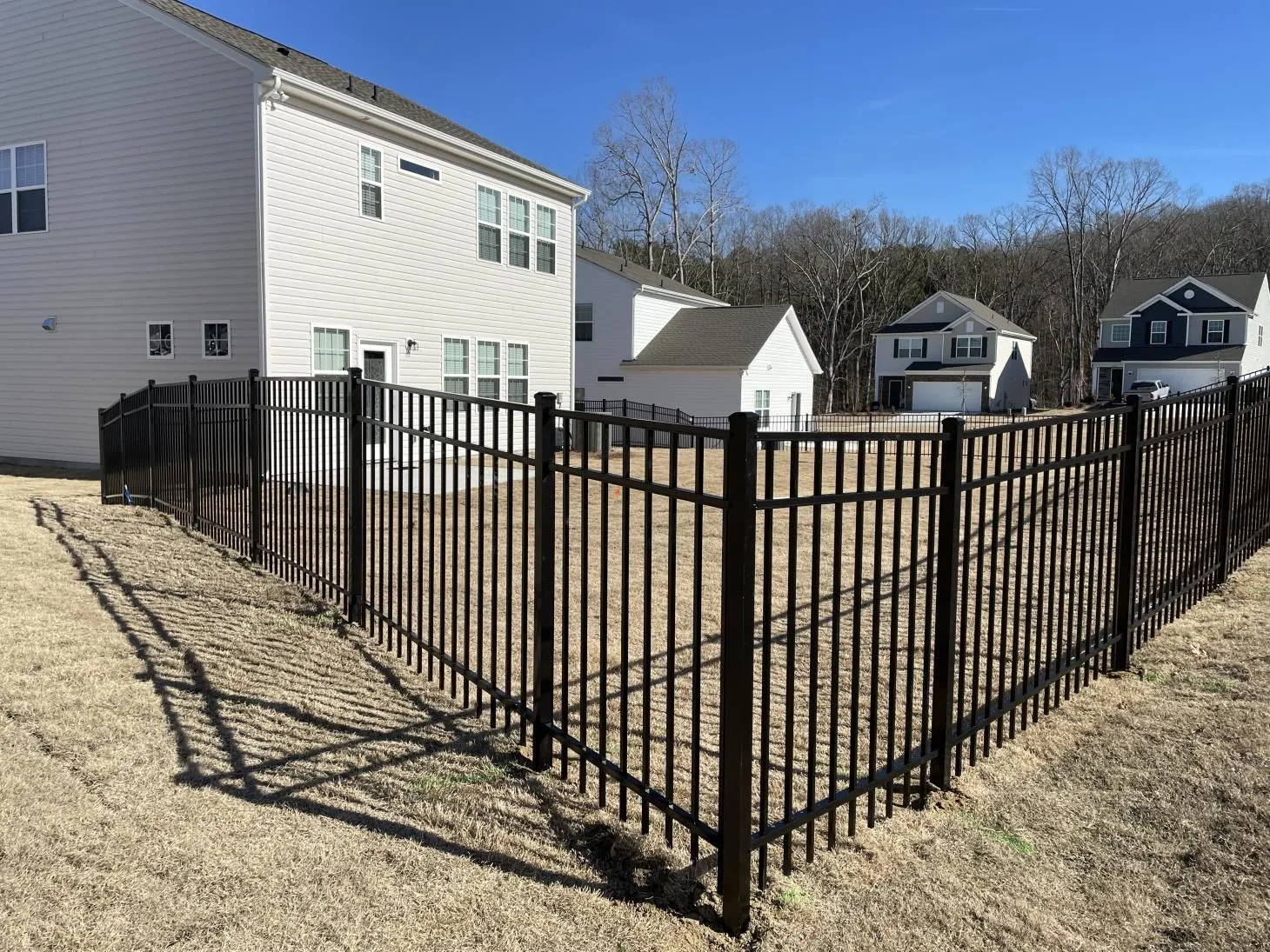 Black metal fence around suburban backyard lawn.