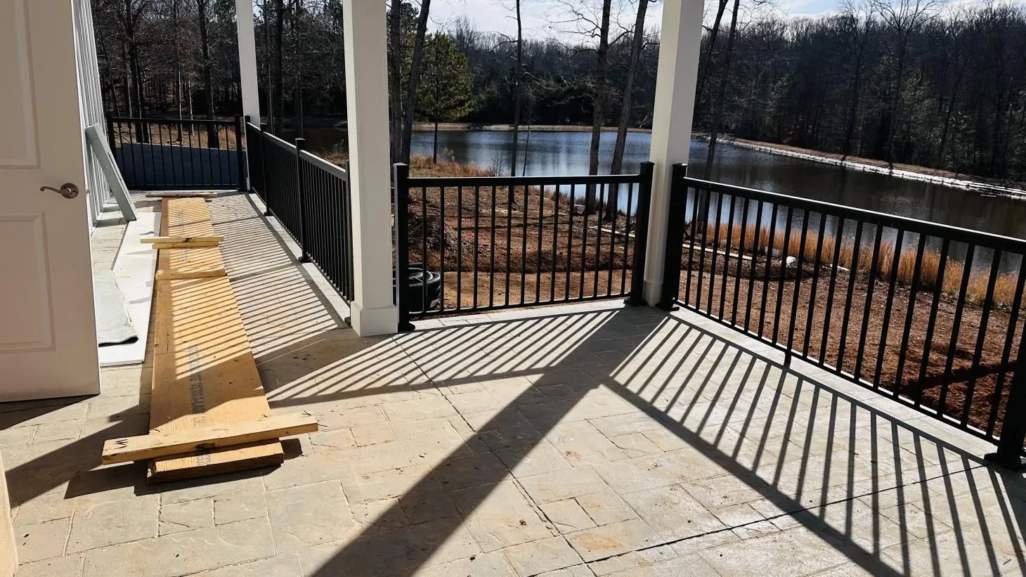 Lakeside porch with black railing and shadows.