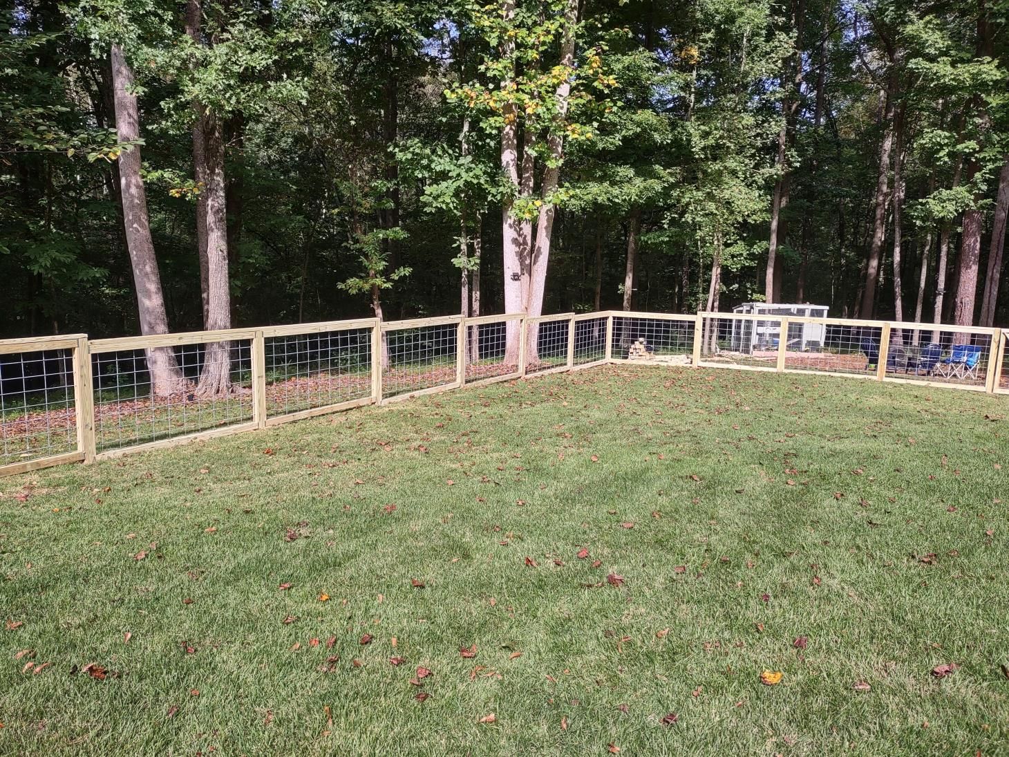 Fenced yard with trees in background.