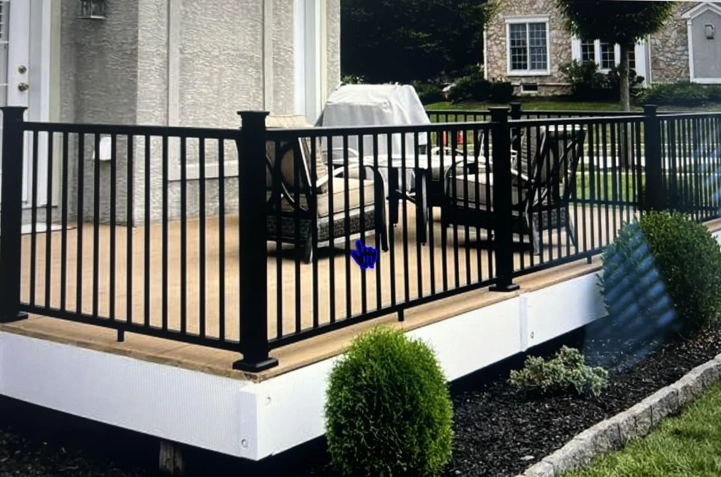 Patio with chairs and black railing.