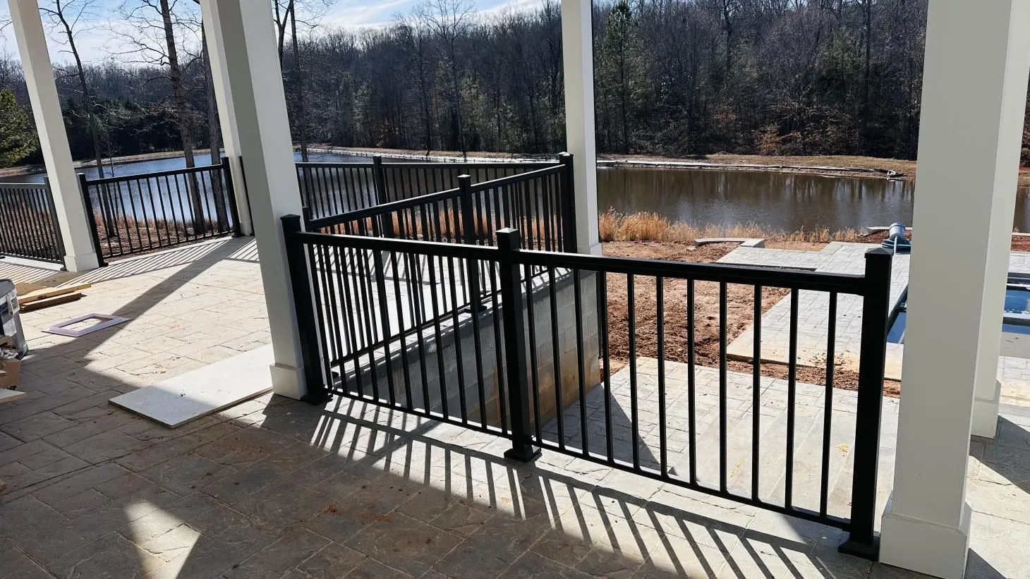 Patio with black railing overlooking a lake.