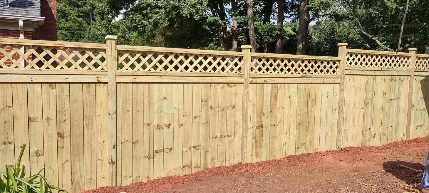 Wooden privacy fence with lattice top design.