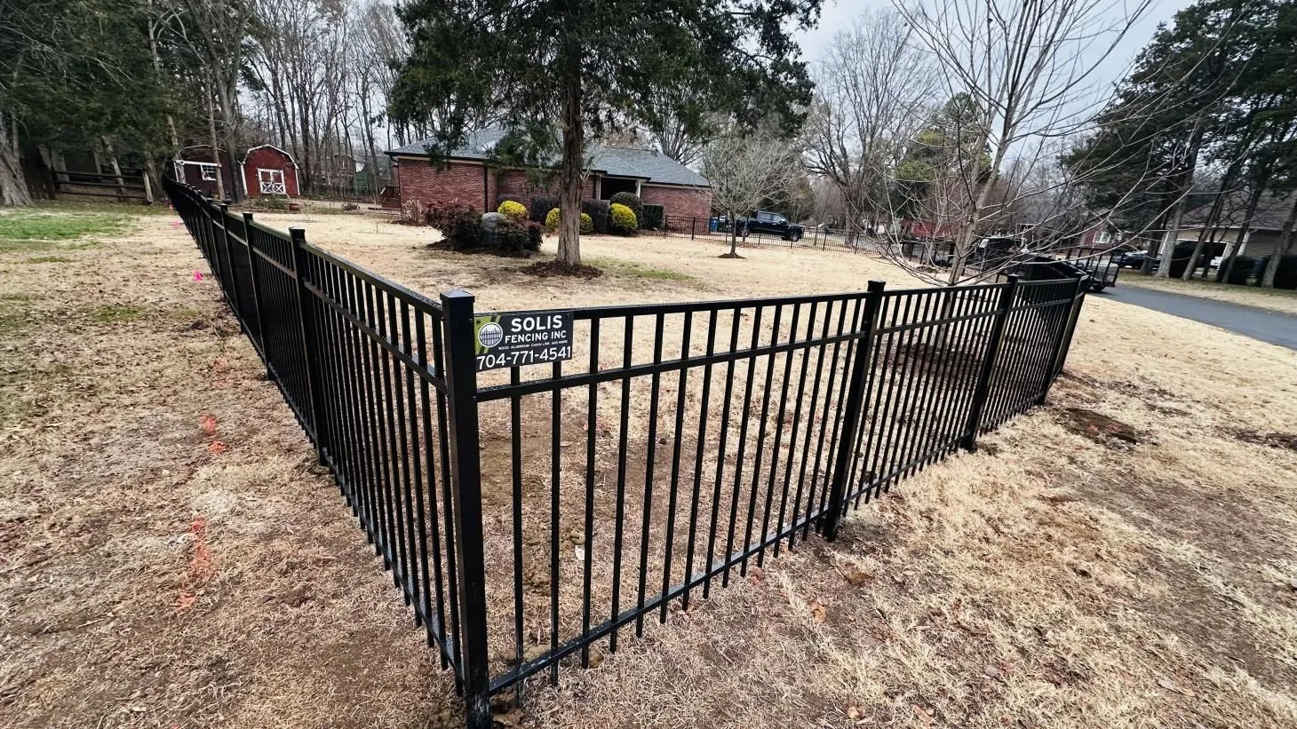 Black metal fence surrounding suburban yard.