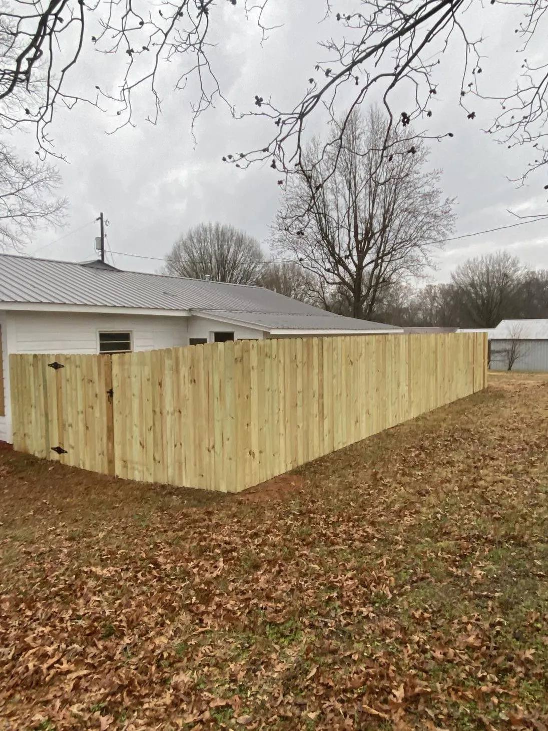 Wooden fence beside house on cloudy day.