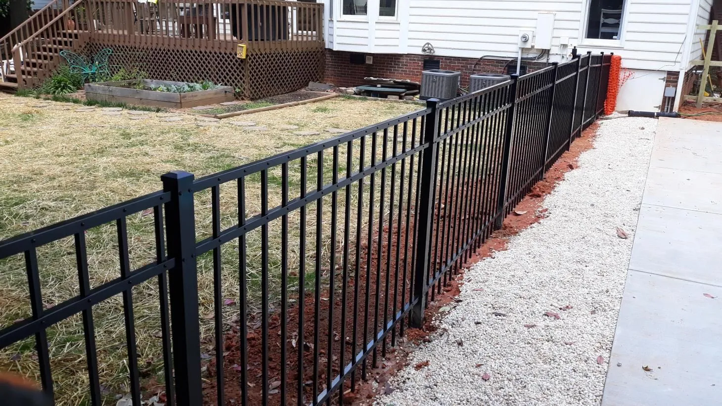 Black metal fence beside gravel and grass.