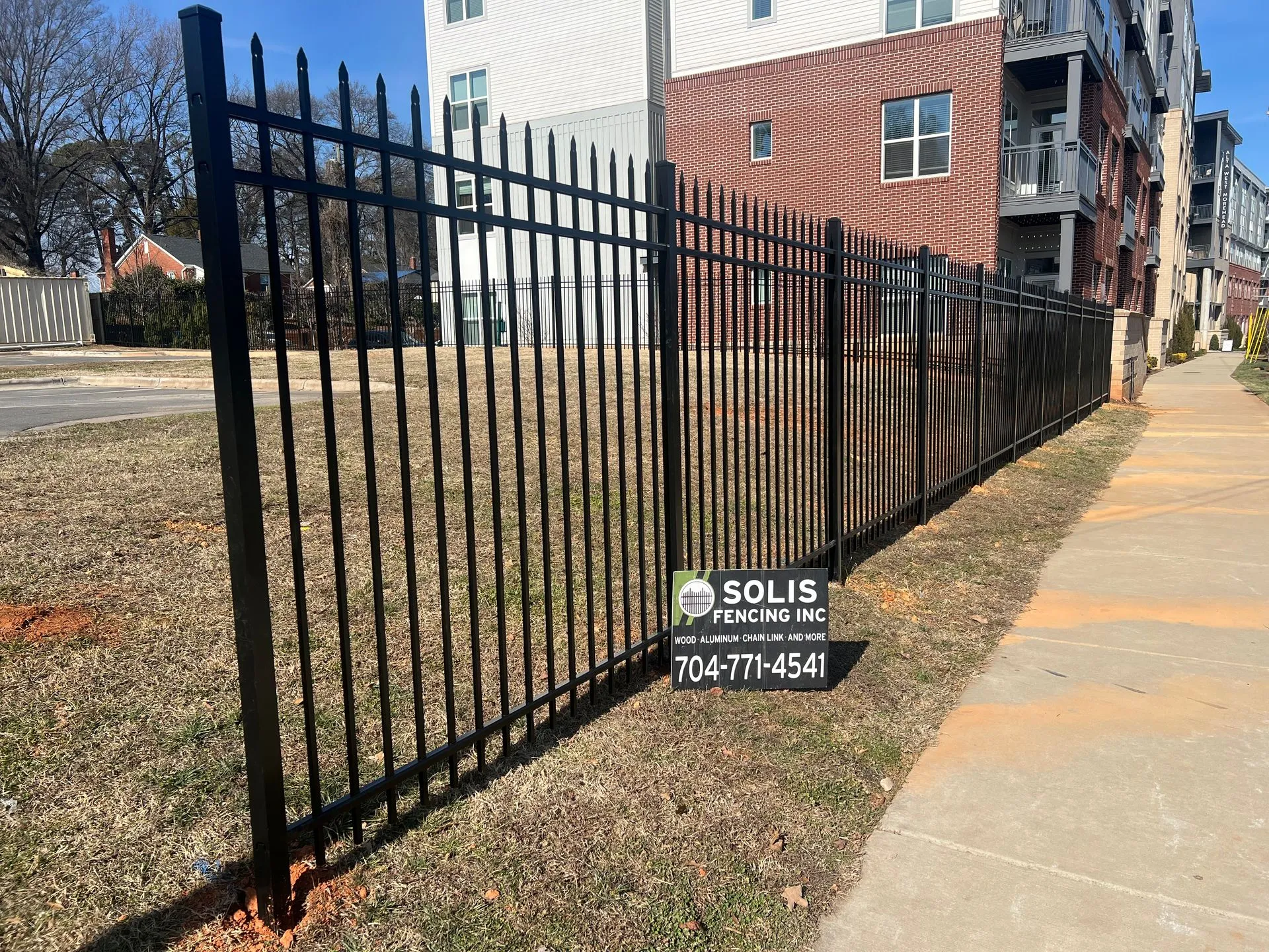 Black metal fence with company sign displayed.