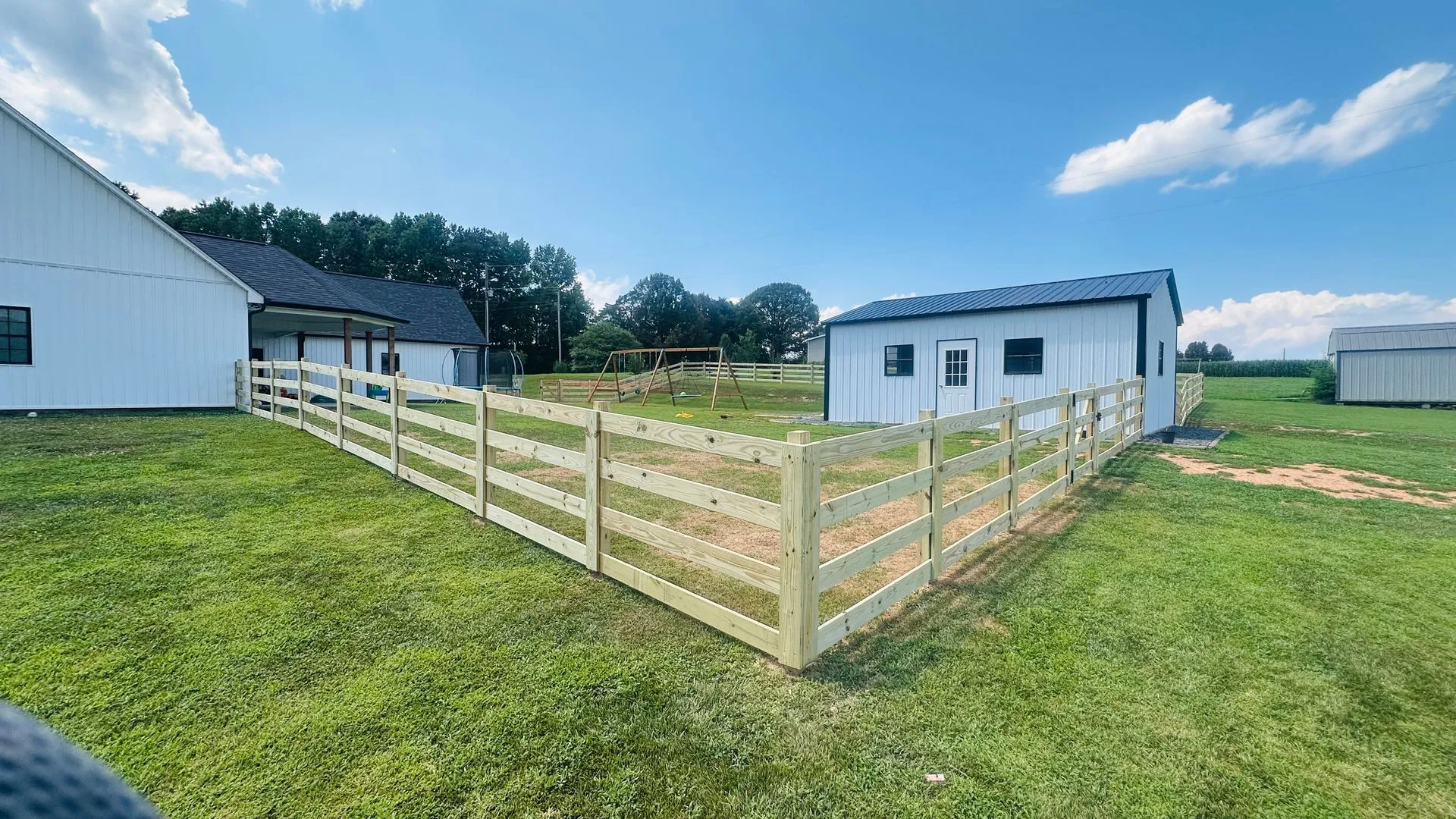 Farm buildings with a fenced grassy area.