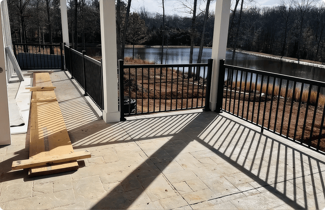 Lakeside patio with wooden planks and shadows.