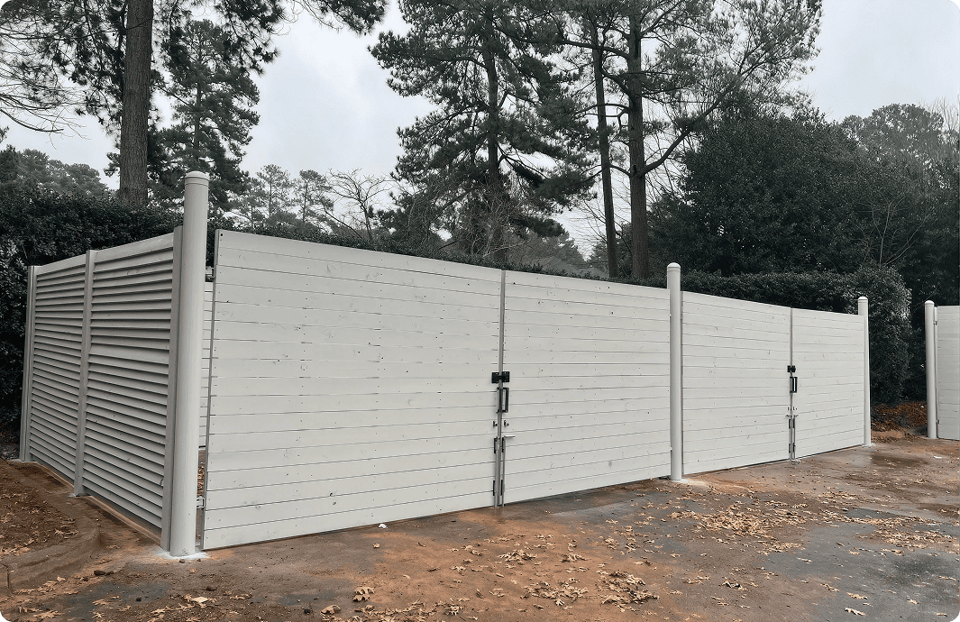 White fence enclosure in wooded area.