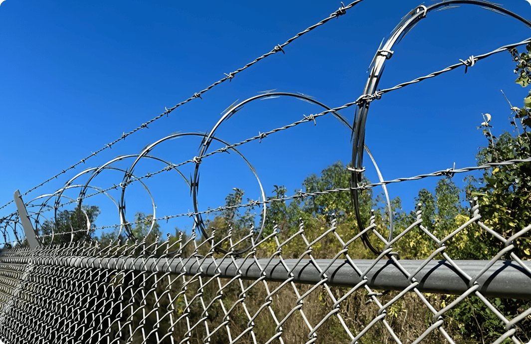 Barbed wire fence under clear blue sky.