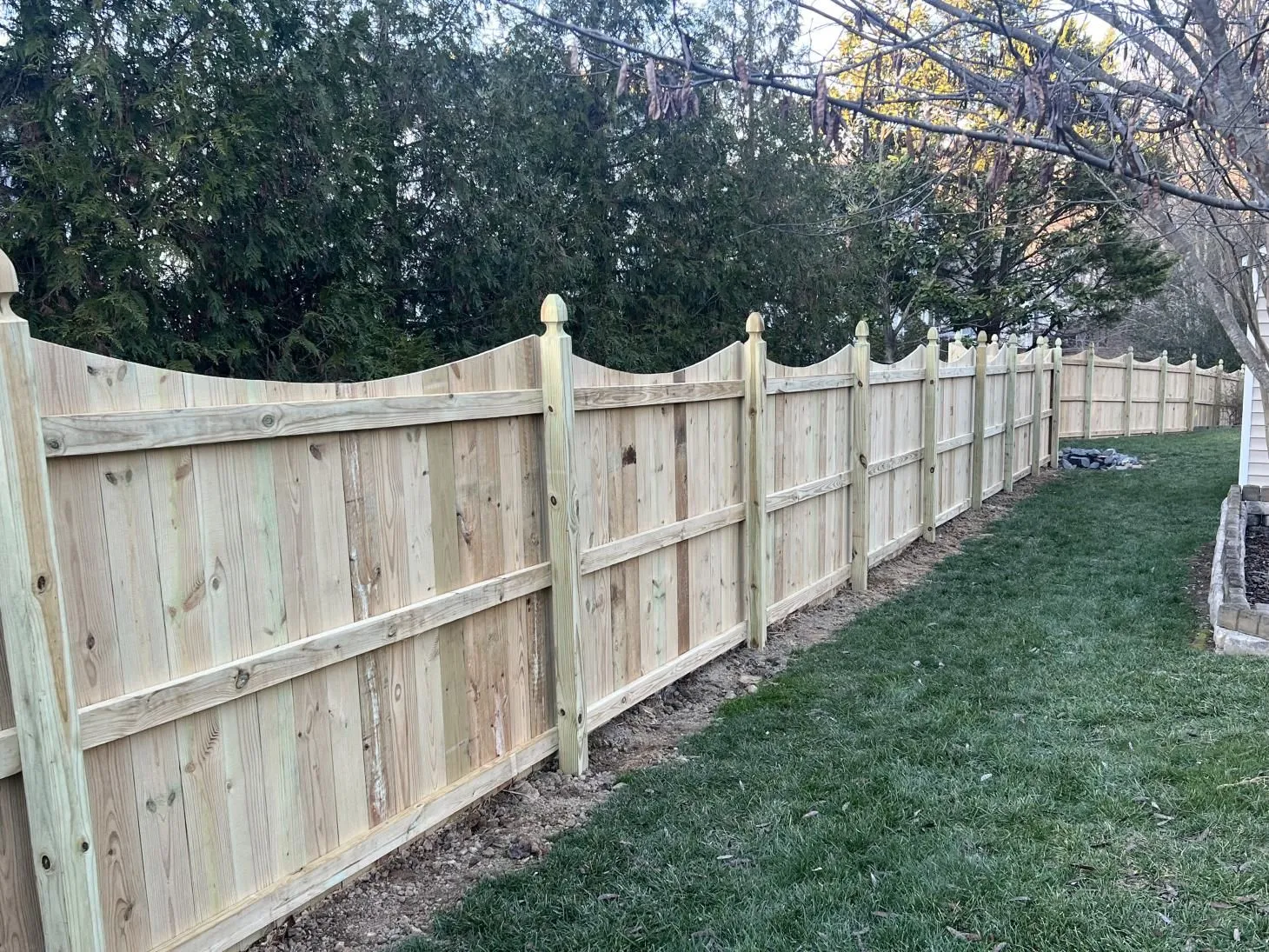Wooden fence along a grassy backyard path.