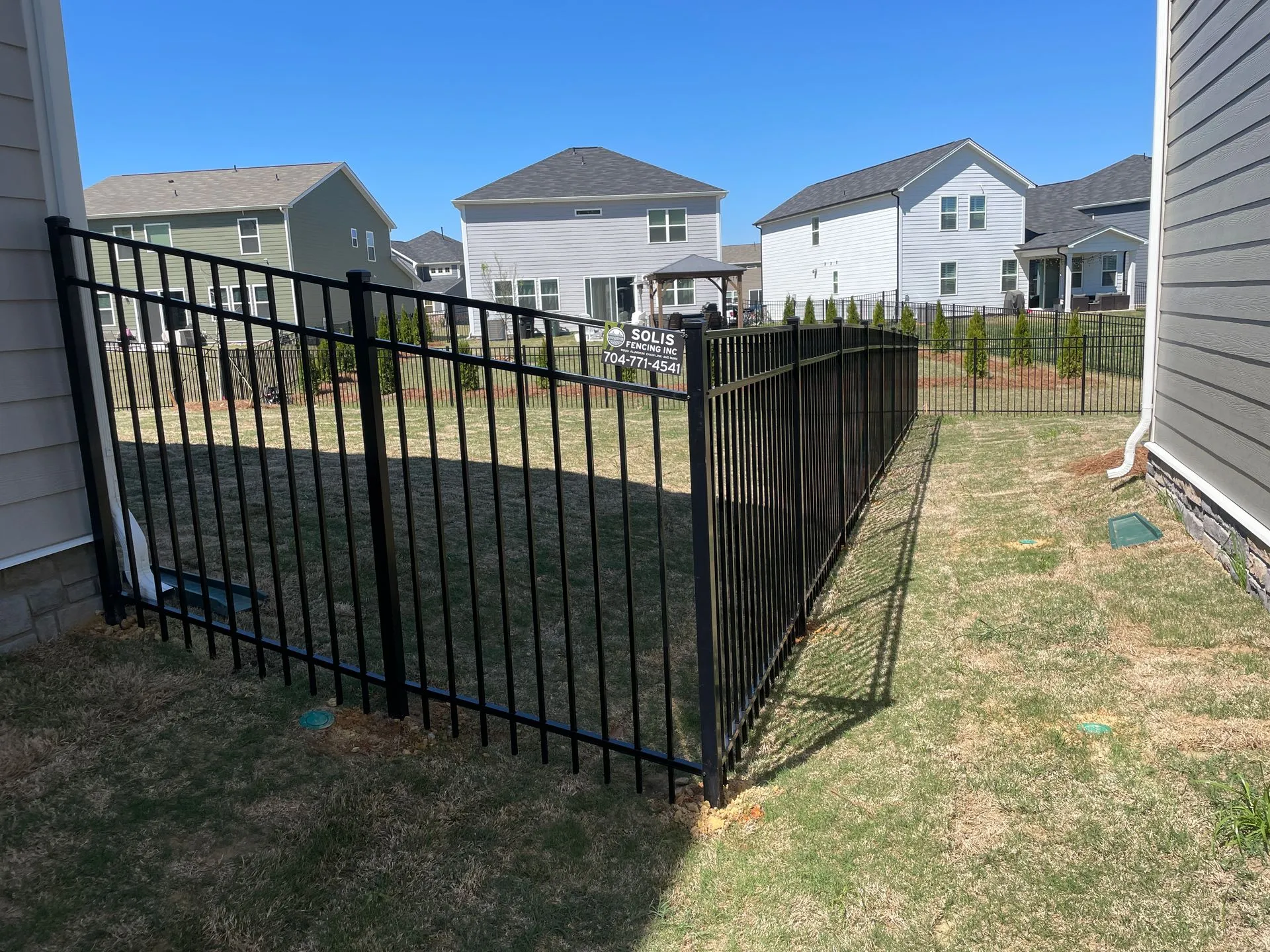 Black metal fence in residential backyard area.