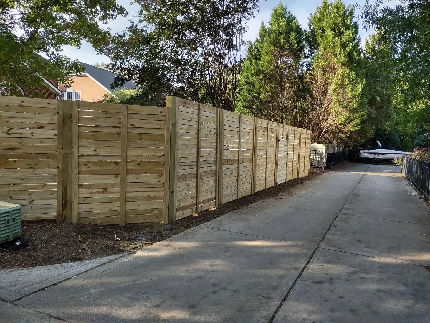 Wooden privacy fence along a paved pathway.