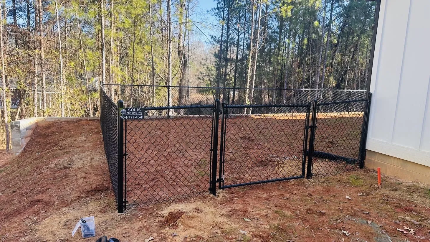 Chain-link fenced area near wooded background.