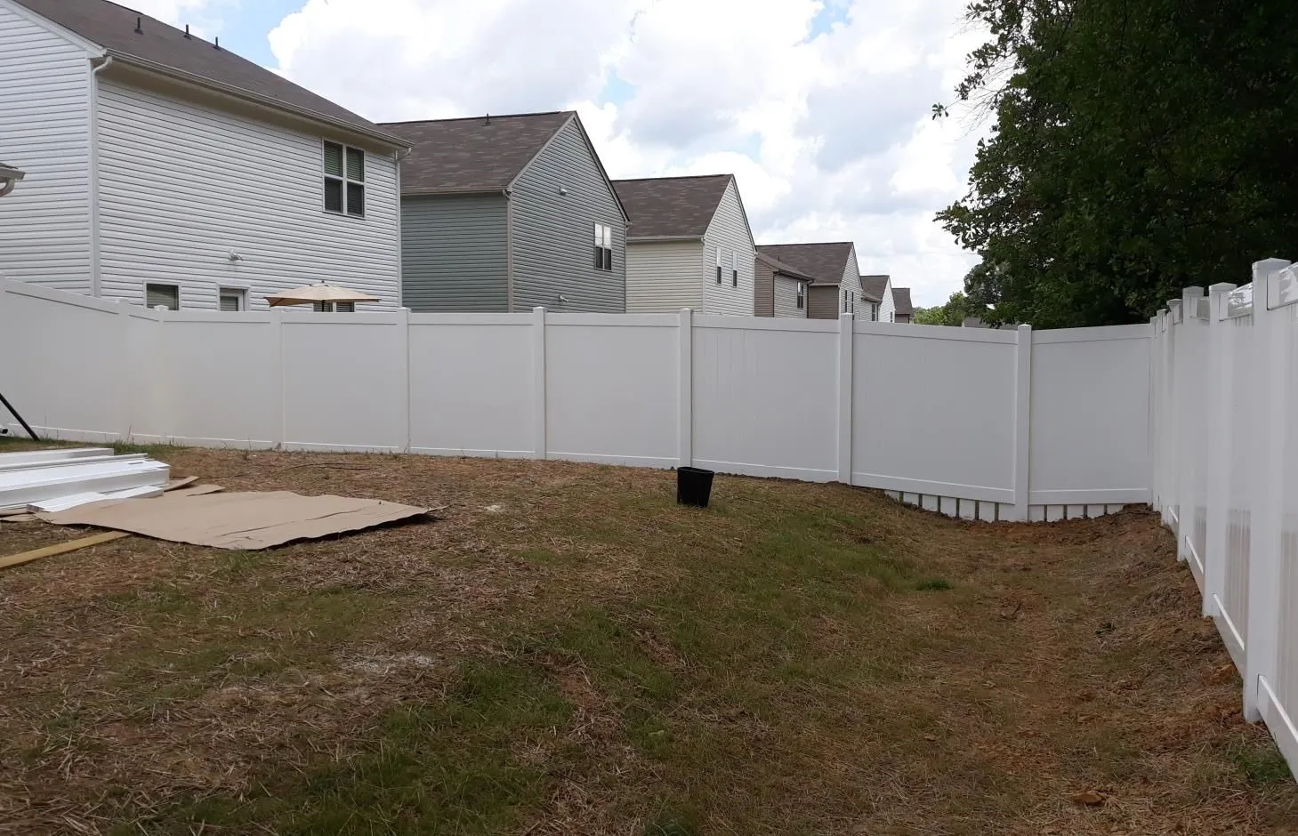 White fence surrounding suburban backyard with houses.