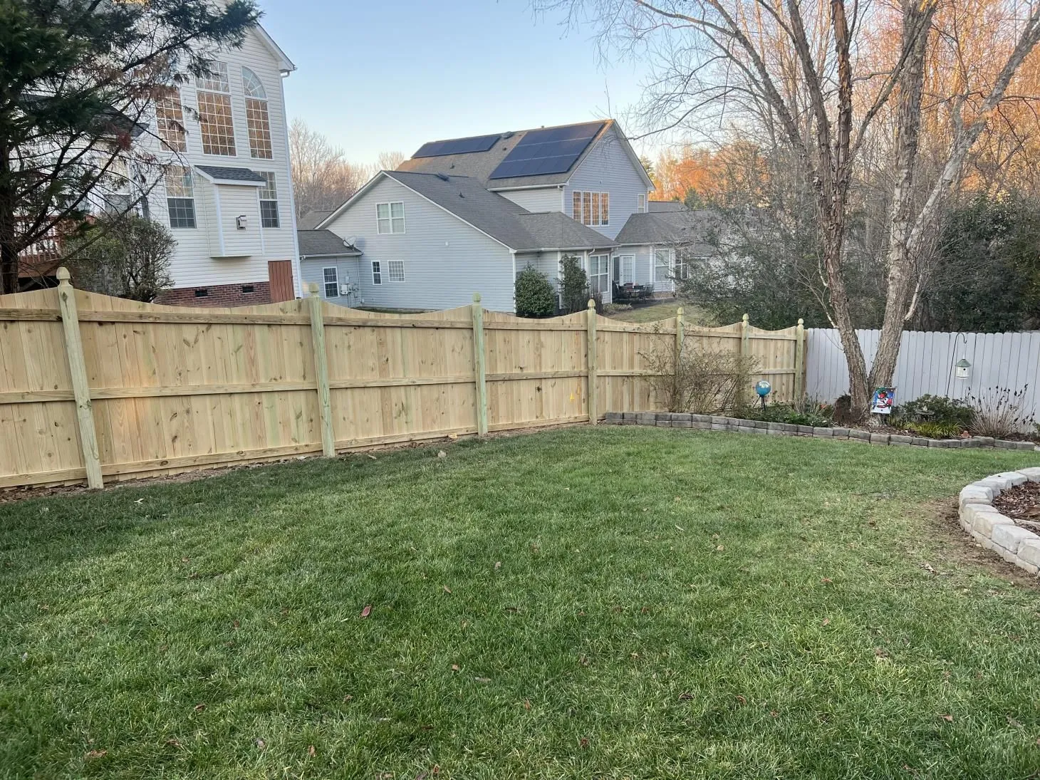 Backyard with wooden fence and grass lawn.