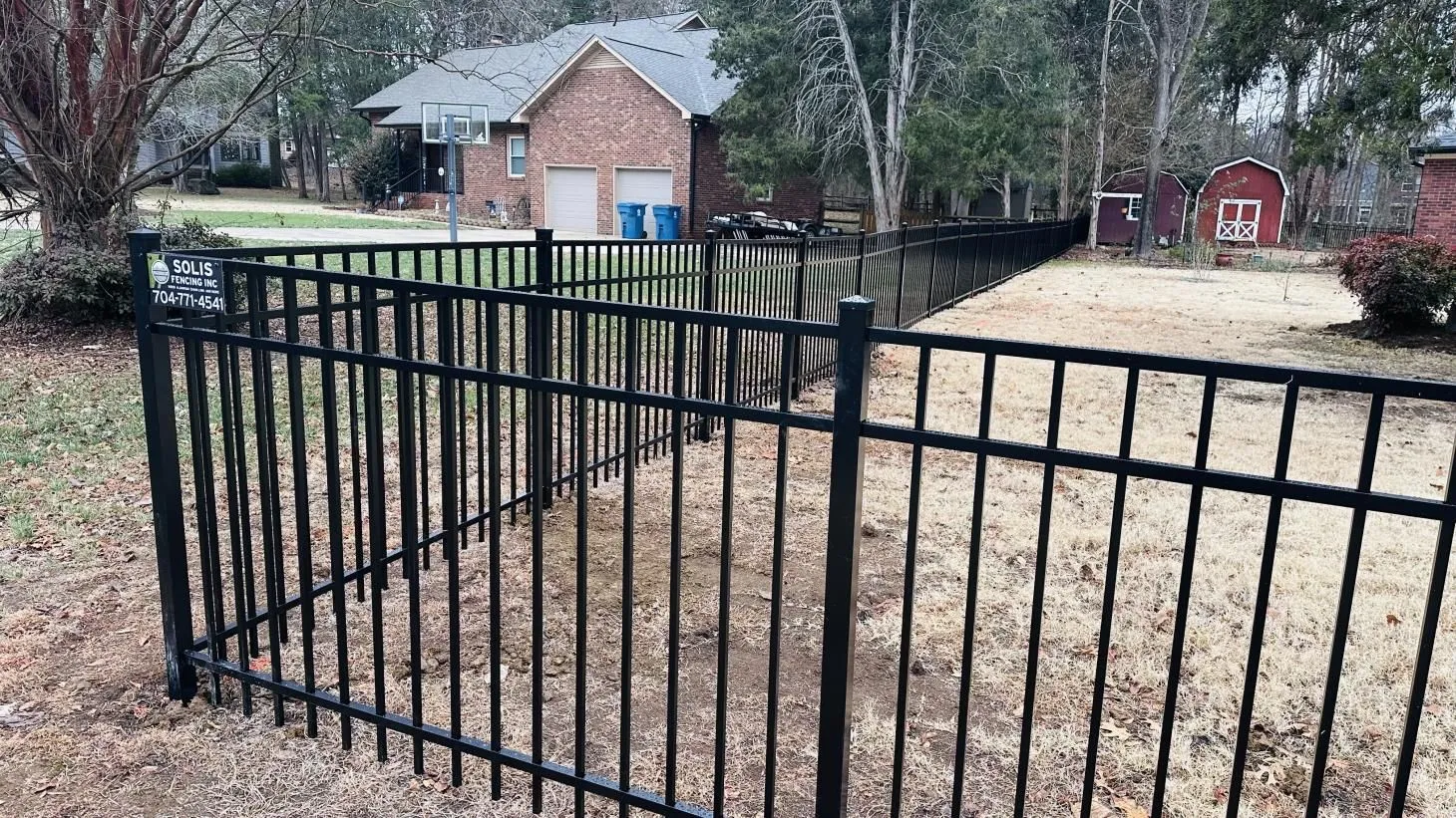 Black metal fence enclosing residential backyard area.