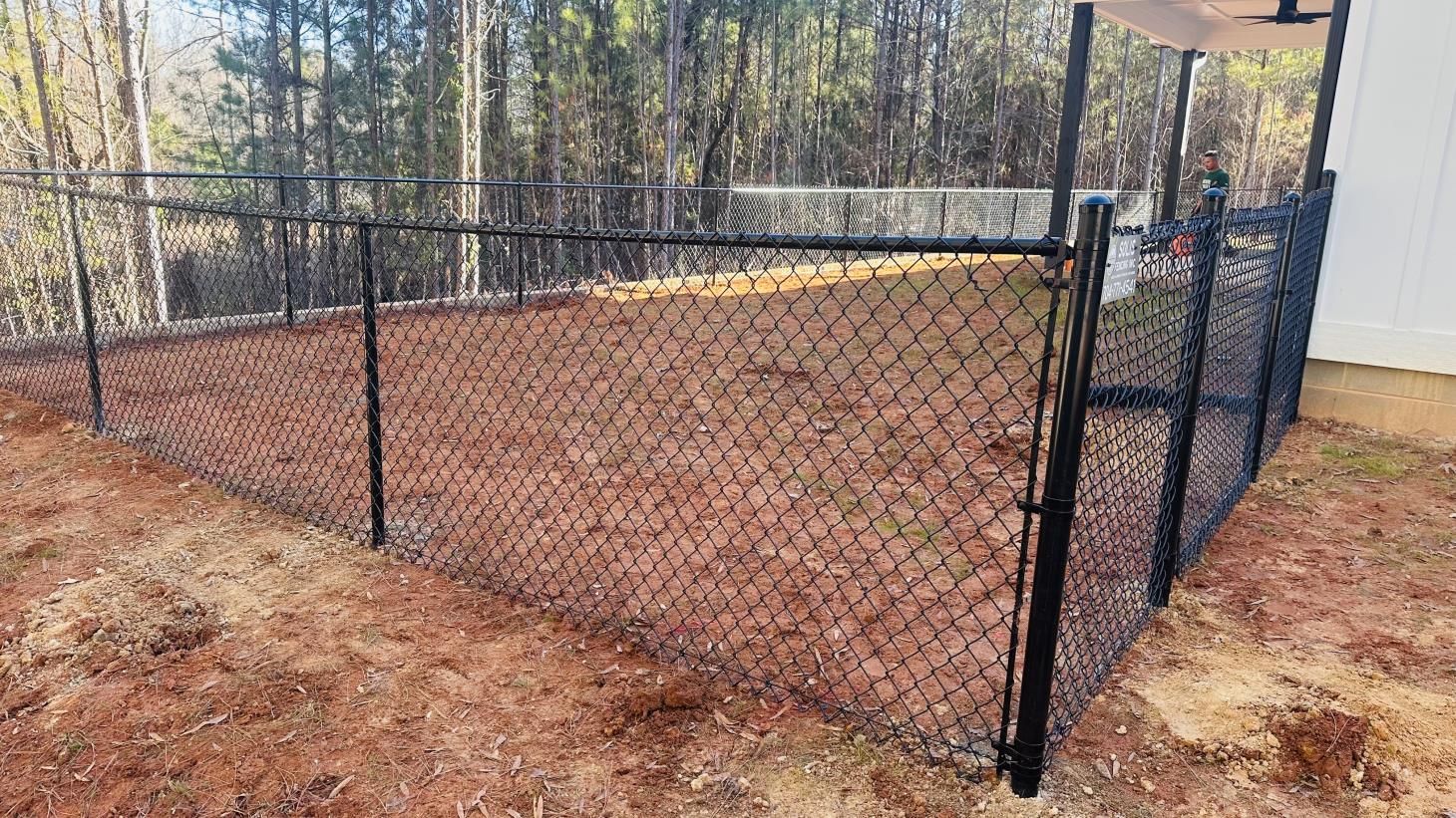 Black chain-link fence around dirt yard.