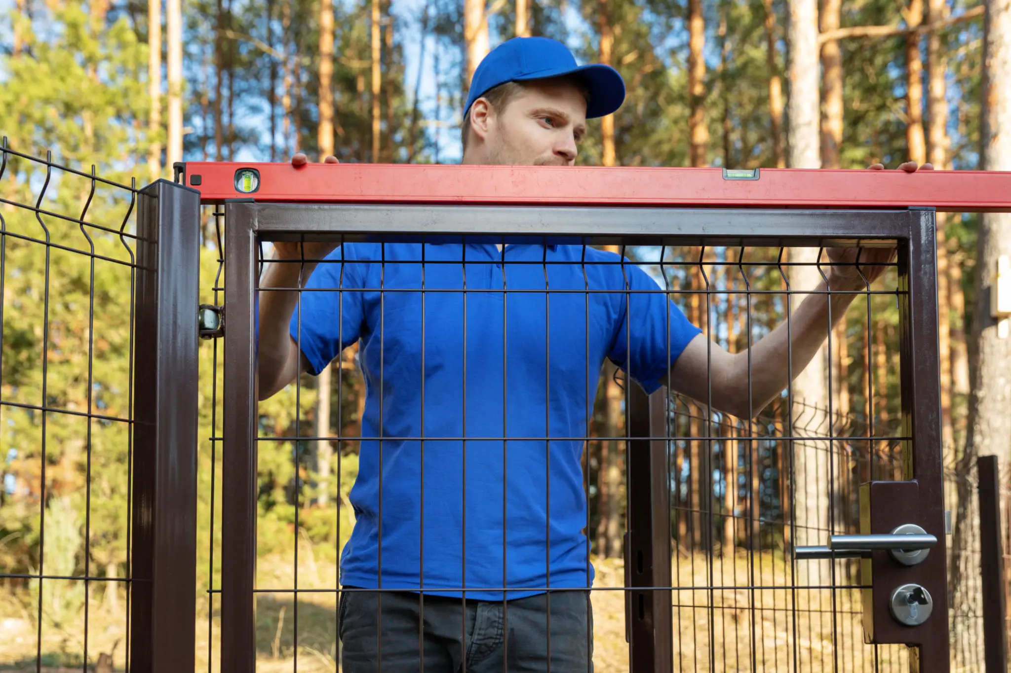 Man leveling metal gate with spirit level