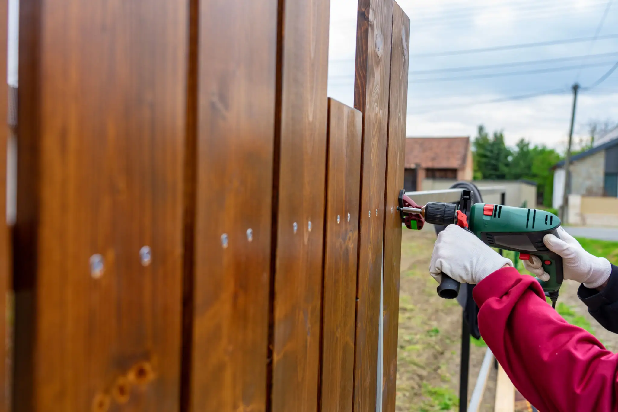 Worker drilling screws into wooden fence panels