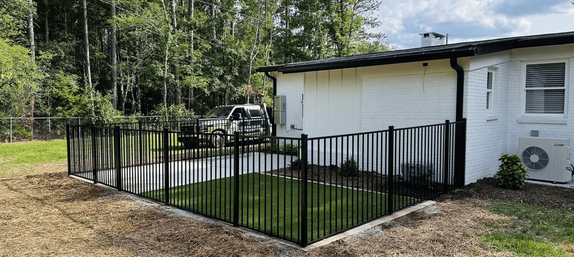 Black metal fence around small grassy area.