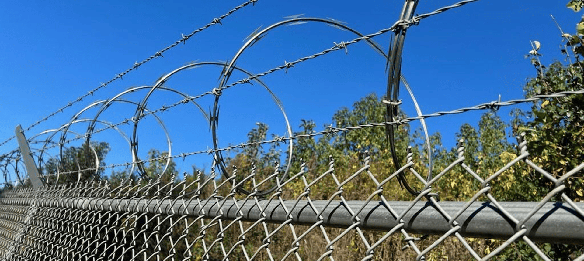Barbed wire fence against blue sky background.