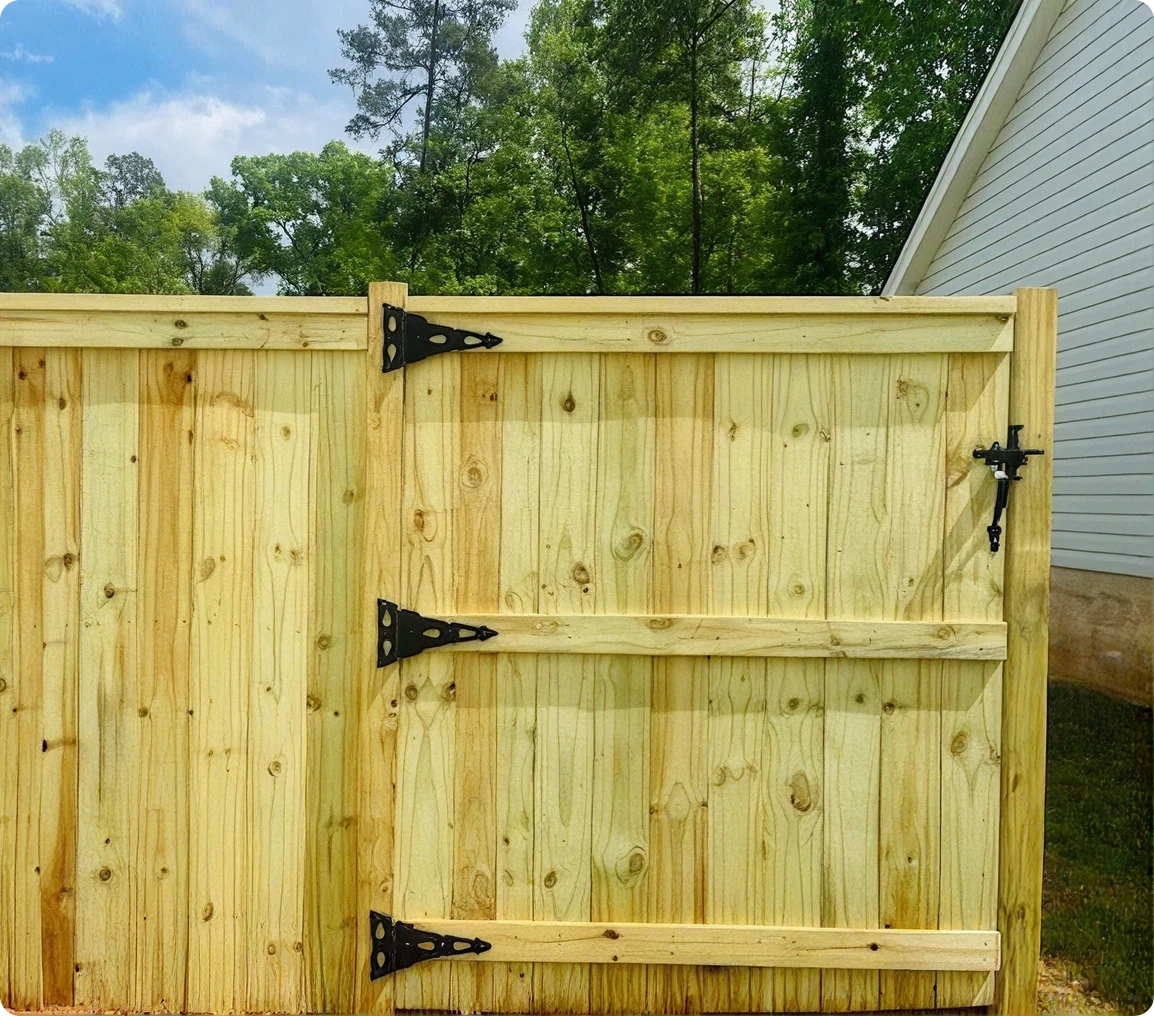 Wooden fence gate with metal hinges outdoors.