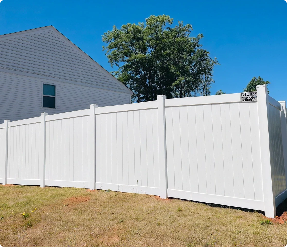 White fence beside a house and tree.