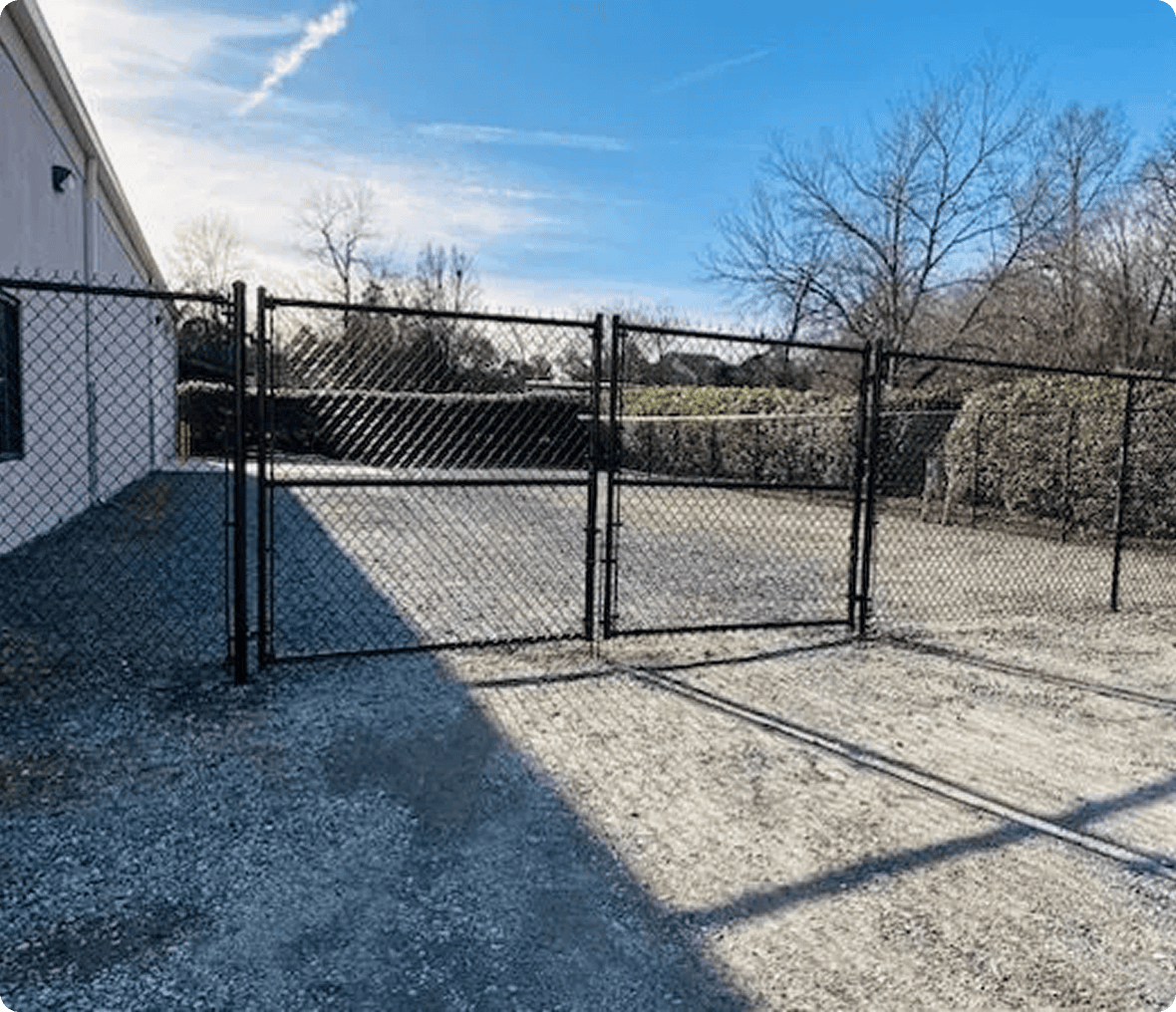 Chain-link fence gate with gravel ground.