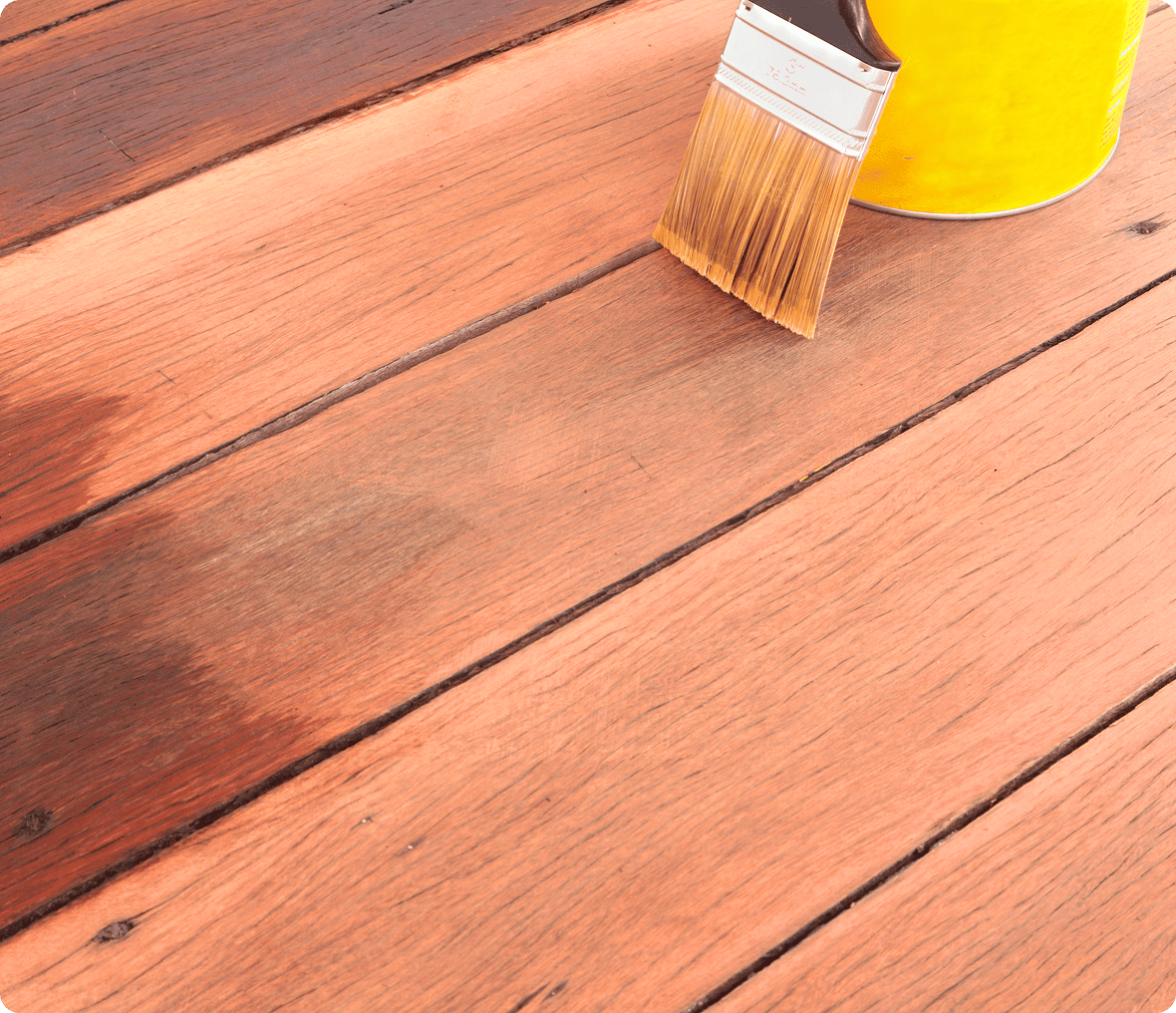 Painting wooden deck with brush and can.
