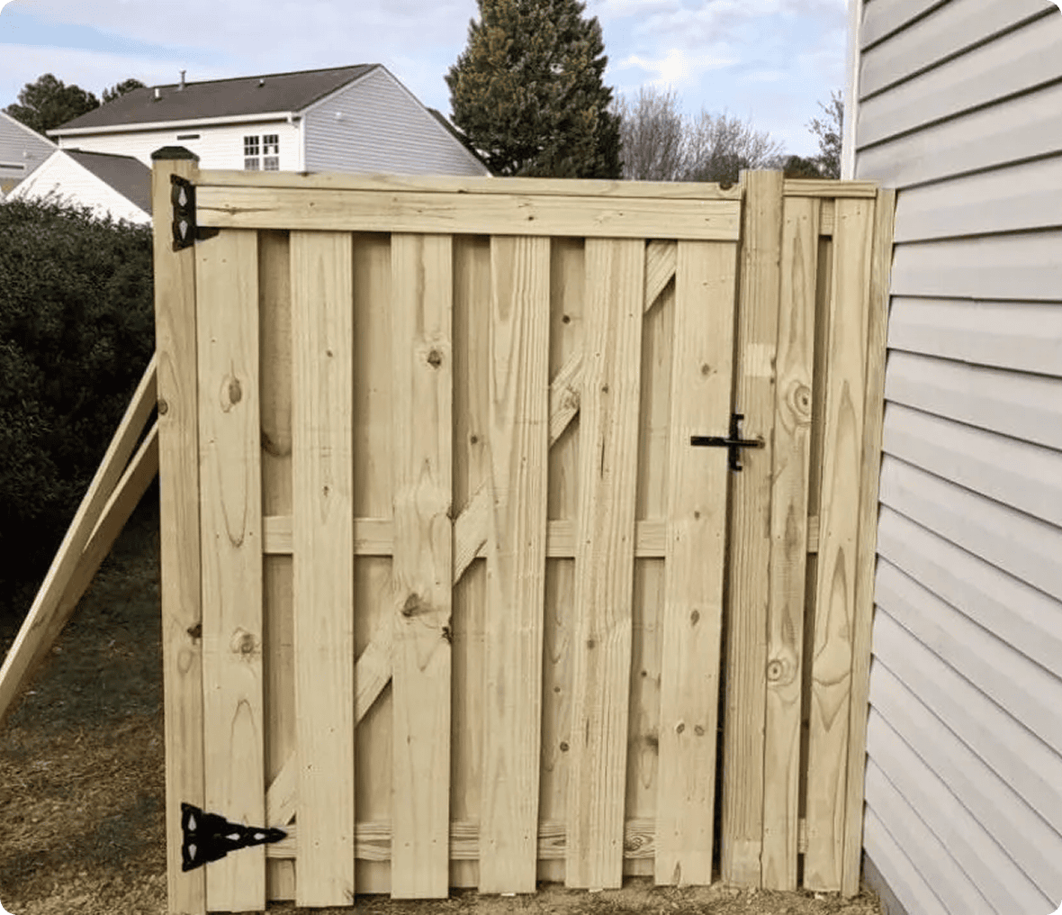 Wooden fence gate beside a house wall.