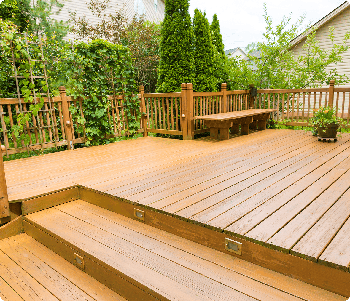 Wooden deck with steps and greenery.