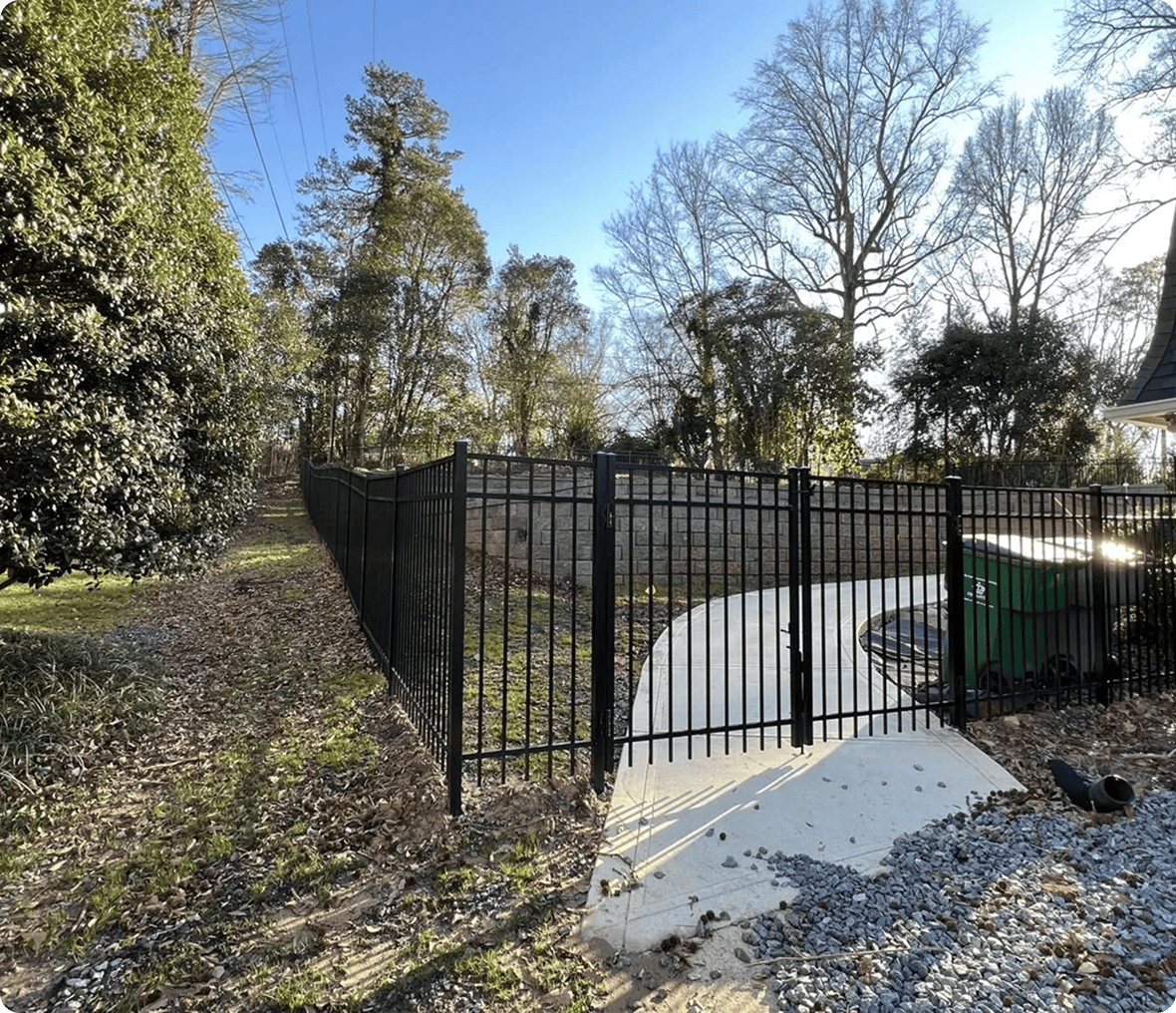 Black metal fence beside paved walkway.