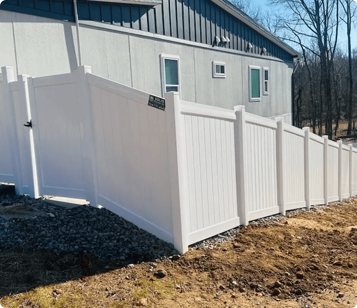 White fence beside a gray building.