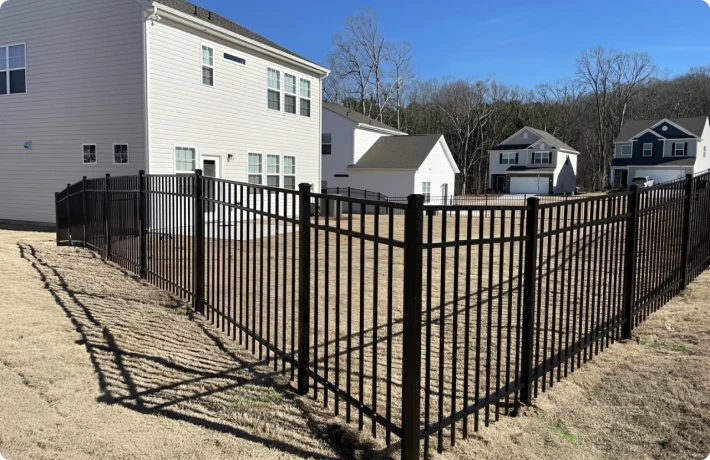 Black metal fence around suburban backyard.