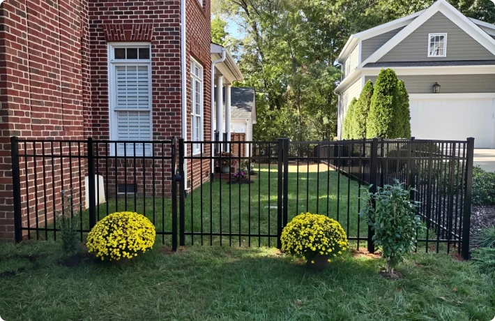 Brick house, black fence, yellow flowers, yard.