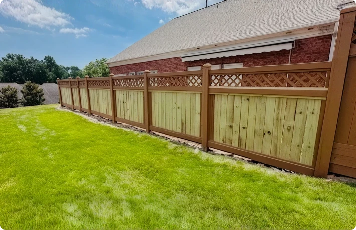 Wooden fence beside a house with lawn.