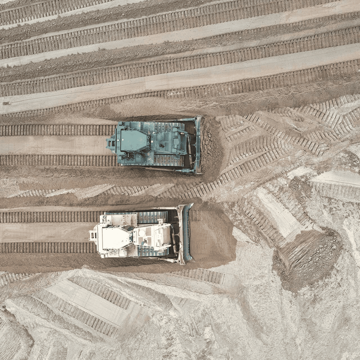 Two bulldozers working on dirt terrain.