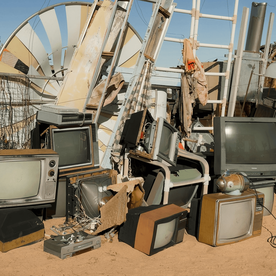 Old televisions stacked outdoors with debris.