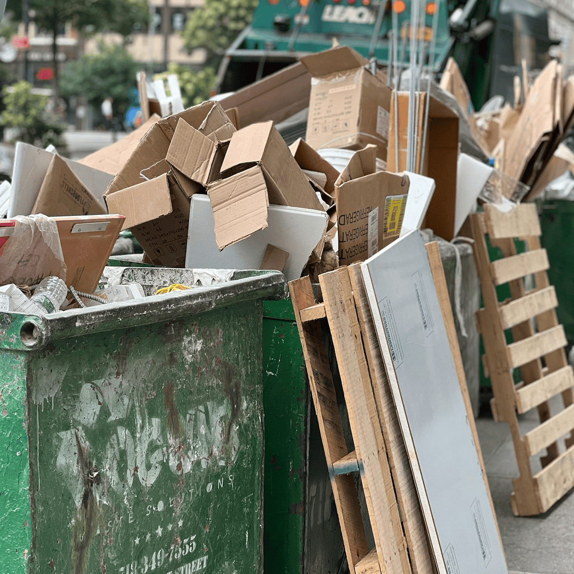 Overflowing dumpster with cardboard and pallets.