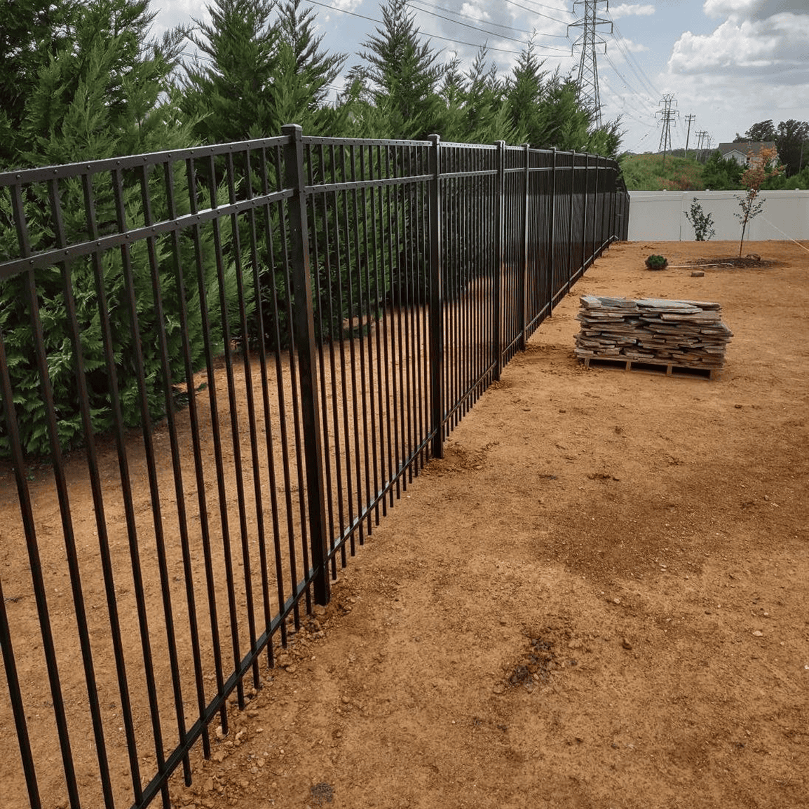 Black metal fence beside dirt path.