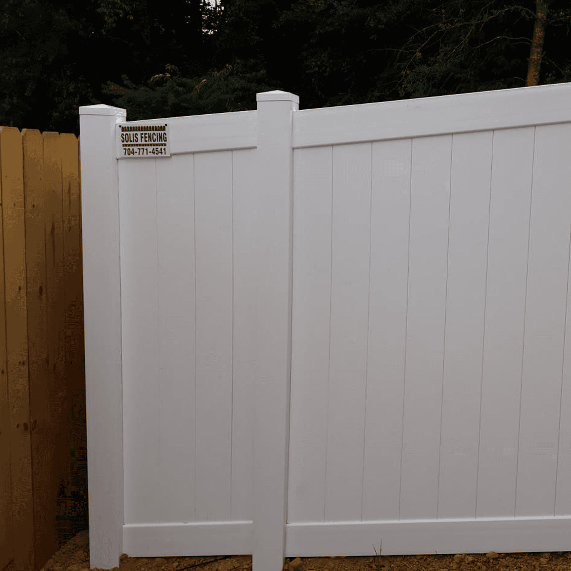 White vinyl privacy fence with contact sign.