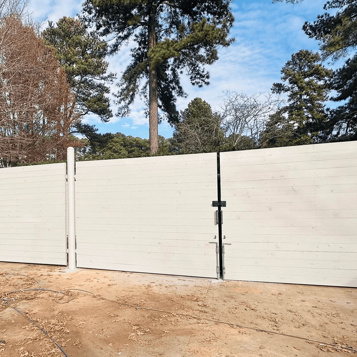 White wooden gate with trees in background.