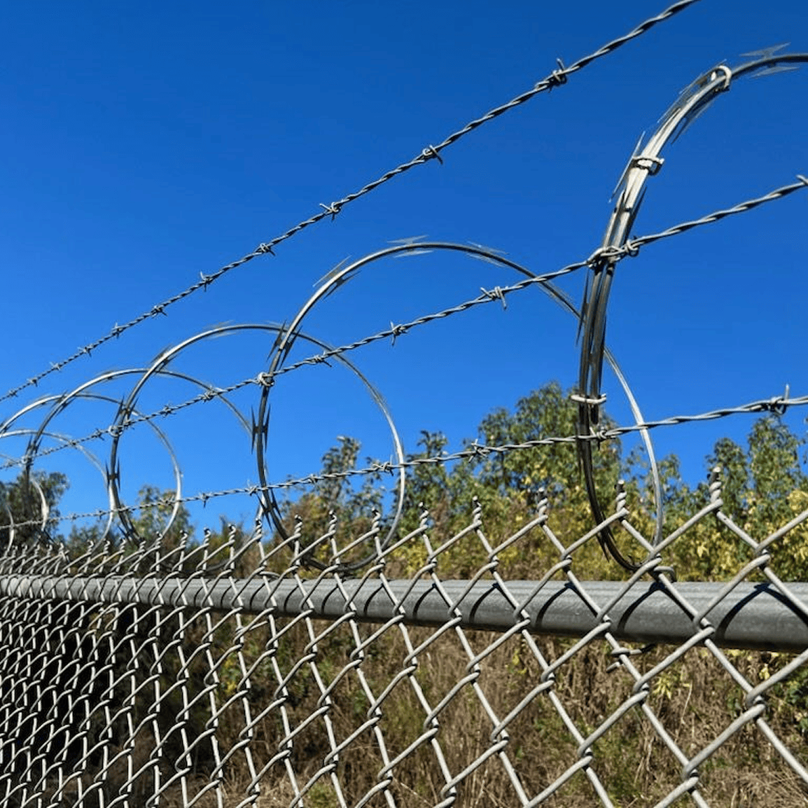 Barbed wire fence under clear blue sky.