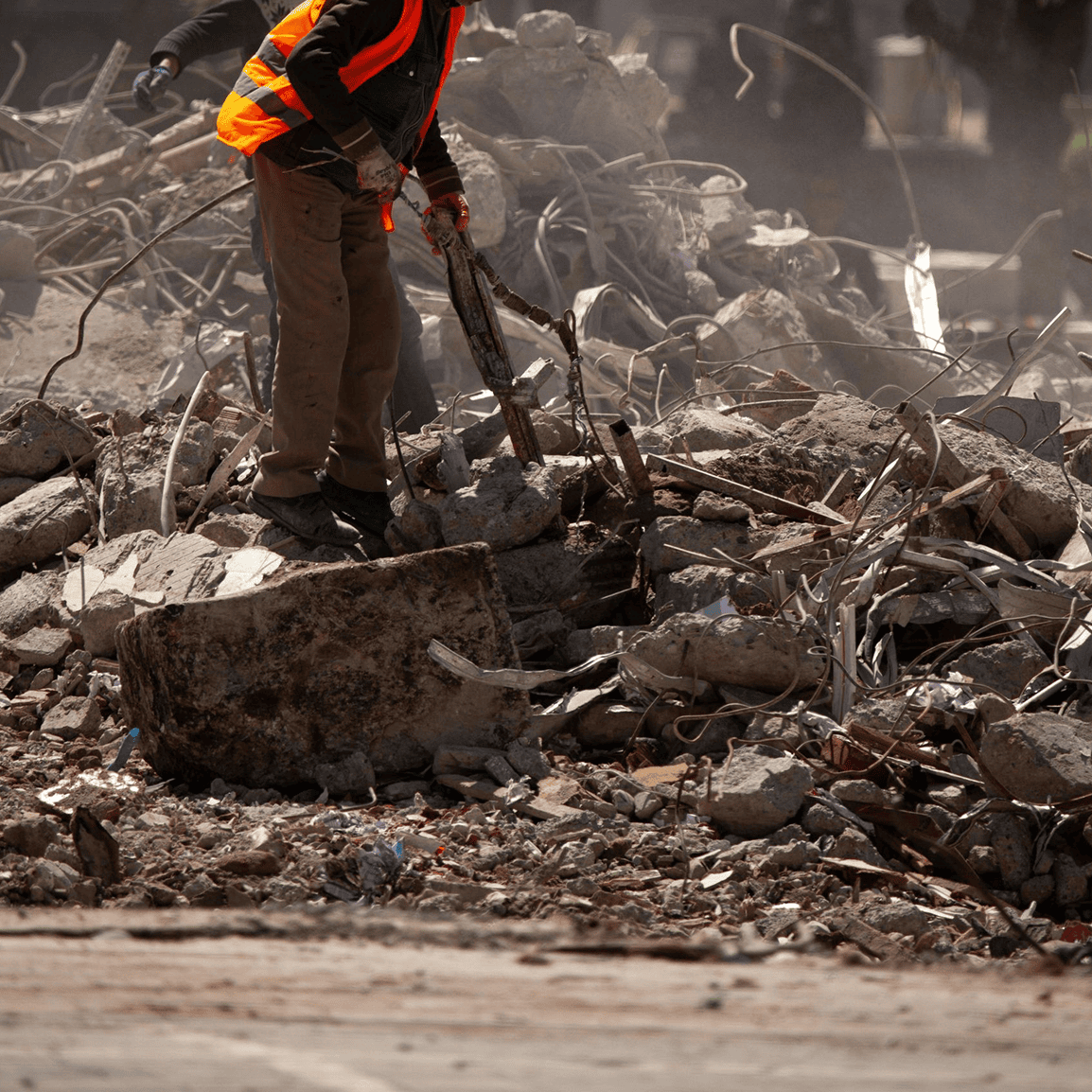 Worker in safety gear amid construction debris.