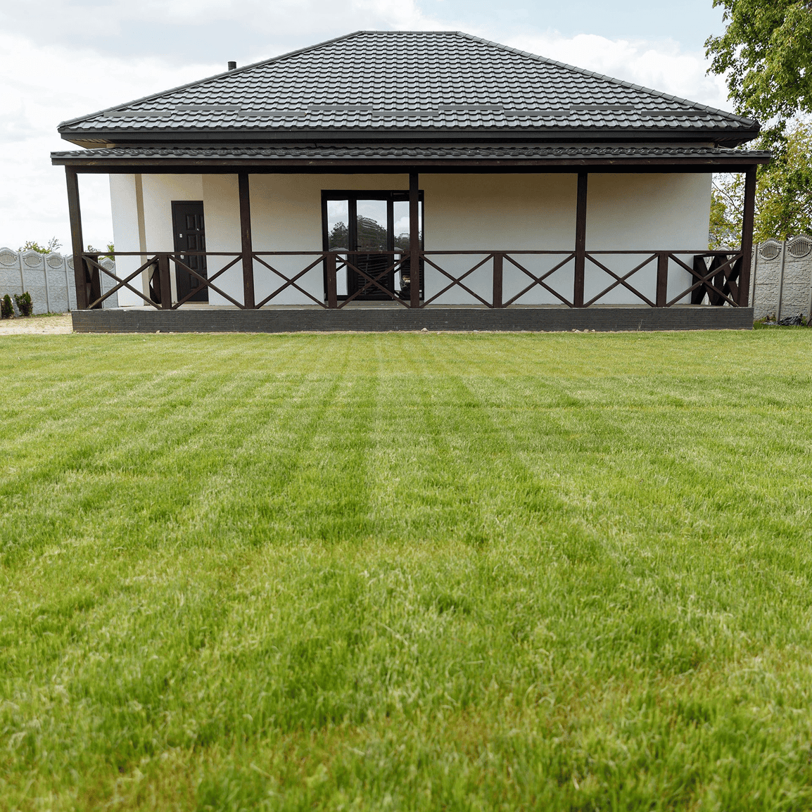 House with porch and large grassy lawn.