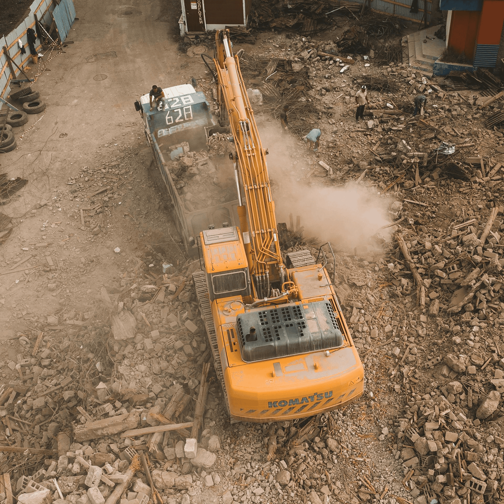 Excavator clearing debris on construction site.