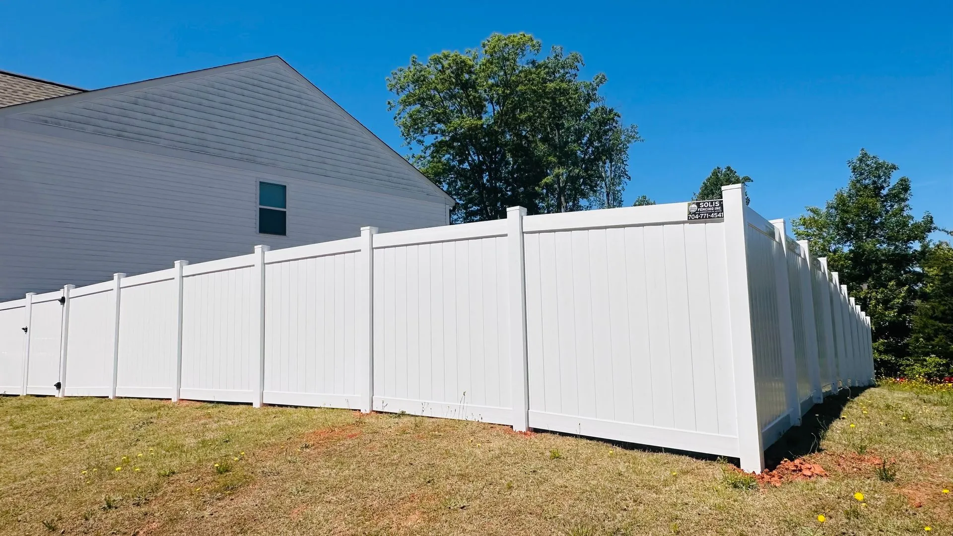 White vinyl fence around a suburban yard.