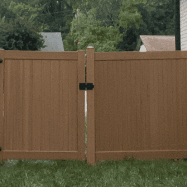 Wooden fence in front of a house, with grass on the ground, trees and buildings in the background