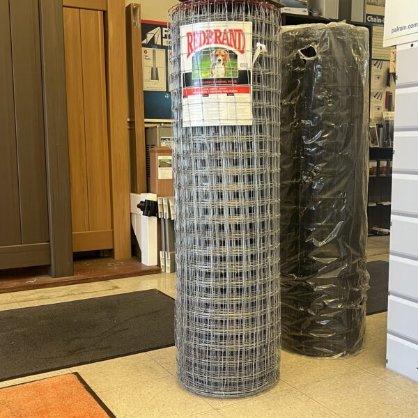 Roll of welded wire mesh in a store, with a poster on the wall behind it